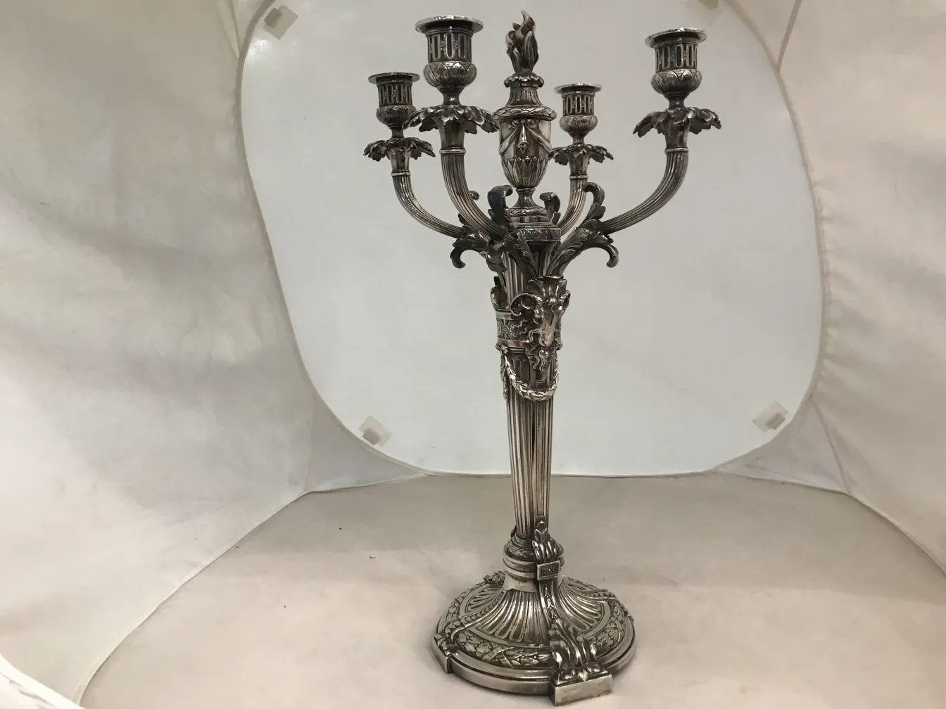 Antiguos candelabros con diseño art nouveau y detalles decorativos, en un ambiente neutral.