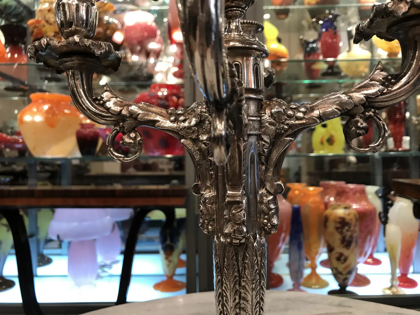 Candelabros antiguos decorados con detalles intrincados en un entorno variado de antigüedades.