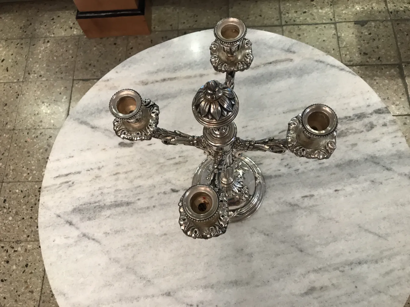 2 candelabros antiguos art nouveau sobre mesa de mármol con entorno neutro.