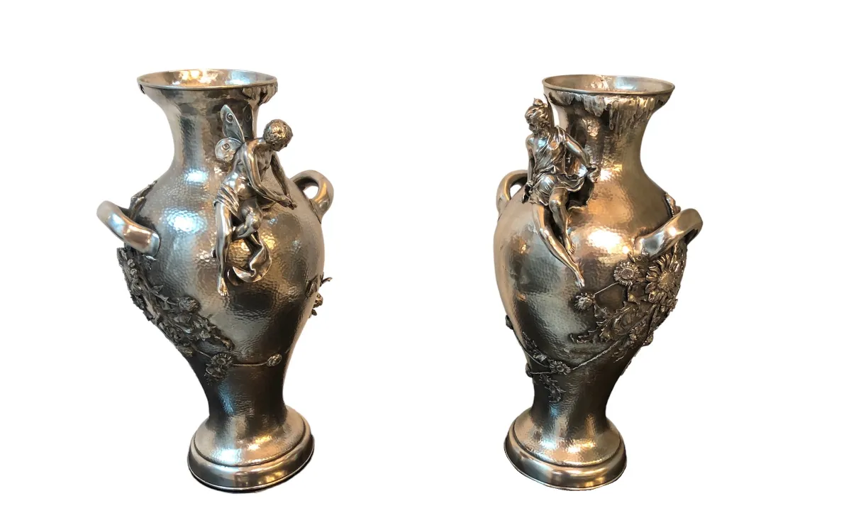 Two antique vases with artistic details and floral decorations, featuring art nouveau design, against a white background.