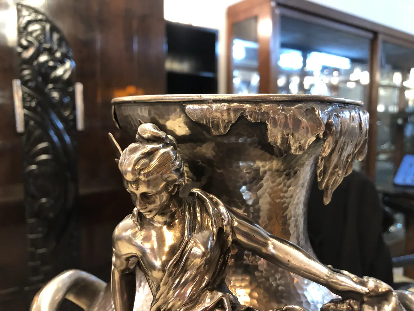 dois vasos antigos em estilo Art Nouveau com decorações elegantes e detalhes finos. Fundos escuros.