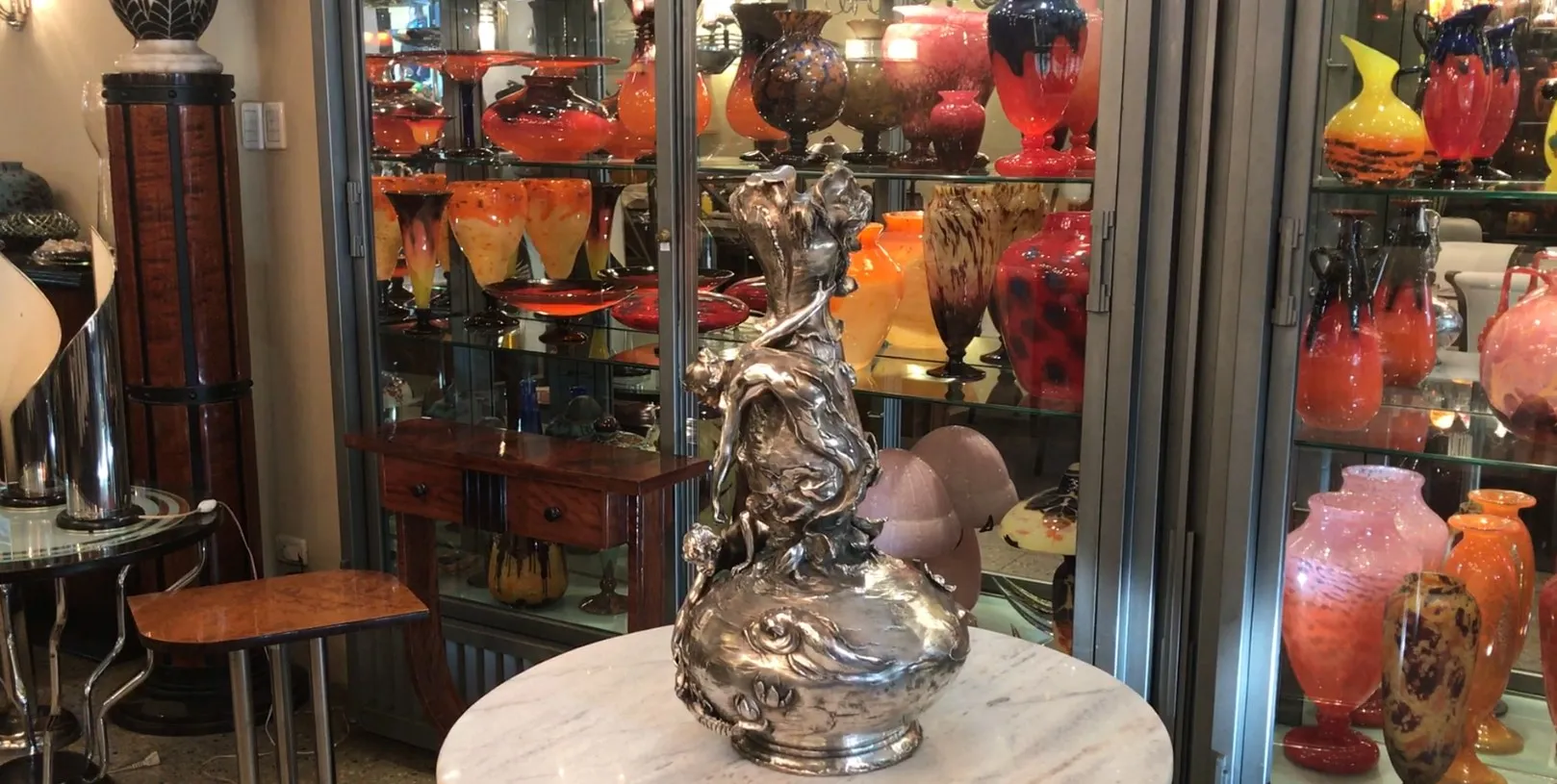 Dos floreros antiguos con diseño art nouveau en un ambiente con otros objetos decorativos.