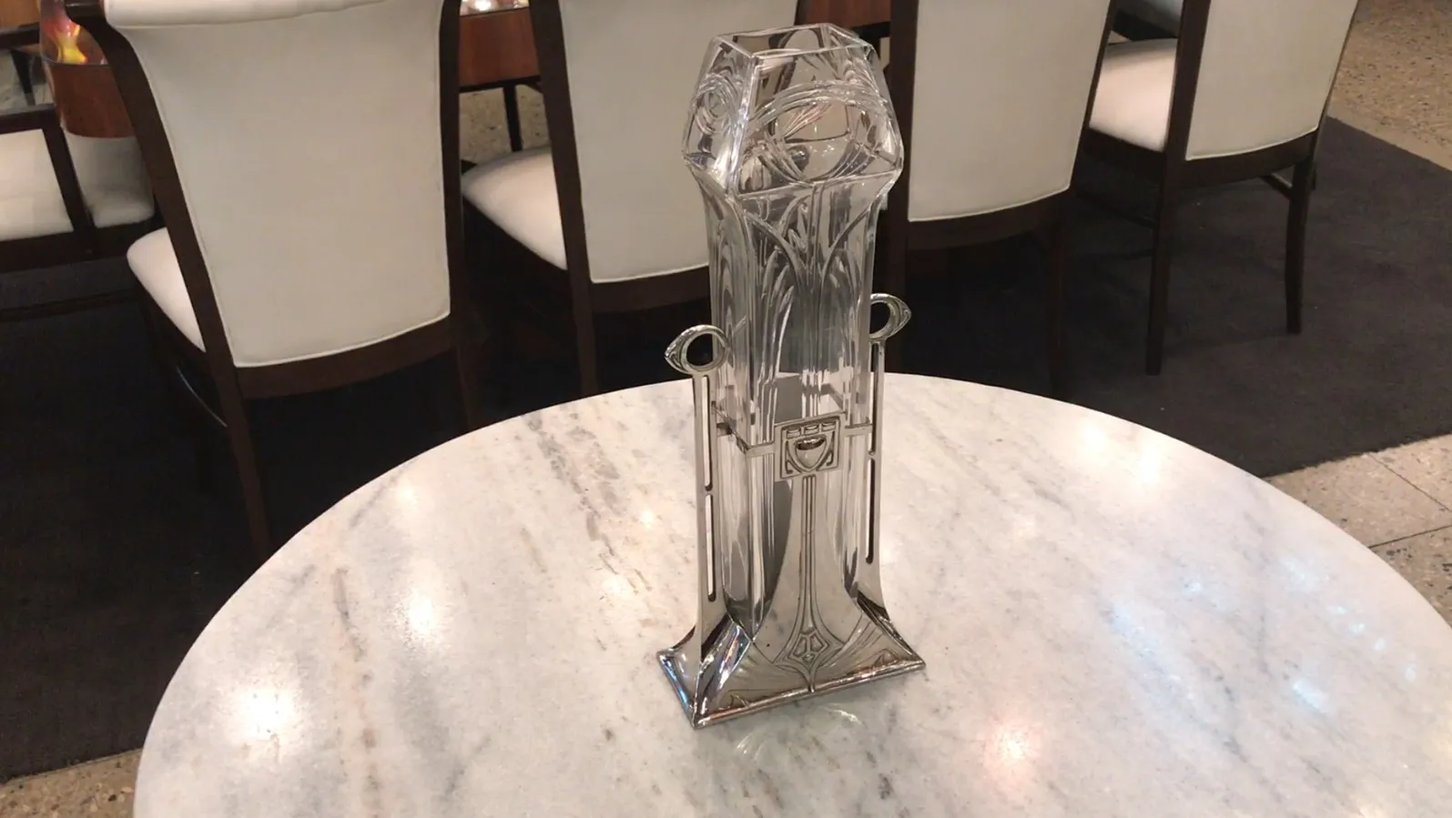 2 vasos antigos com detalhes artísticos e formato elegante, em um ambiente suave de restaurante.