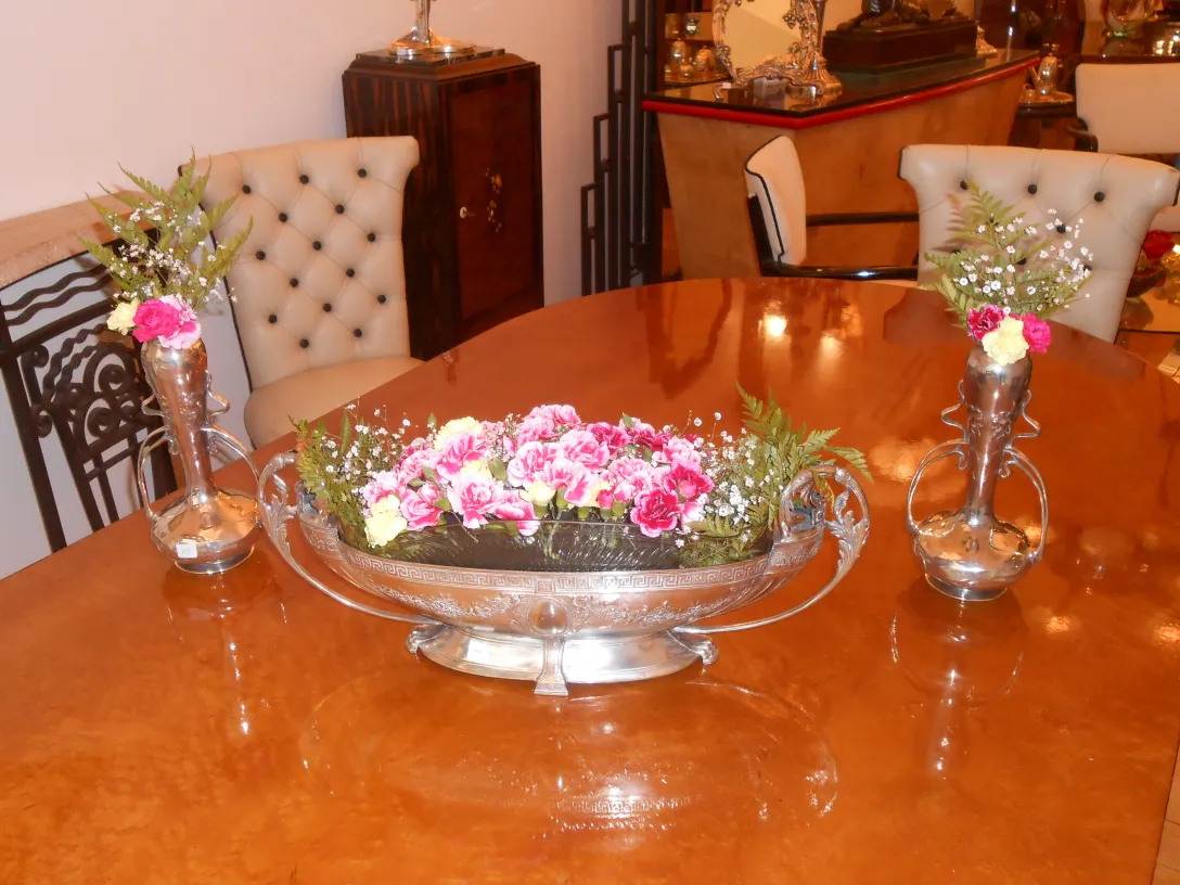 Due vasi antichi Art Nouveau con fiori colorati su un elegante tavolo, circondati da decorazioni d'epoca.