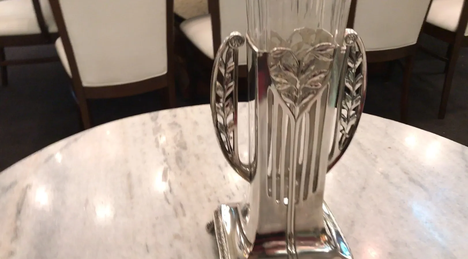 Zwei antike Blumenvasen mit Art Nouveau Design, verziert mit Blättern, auf einem Marmortisch.