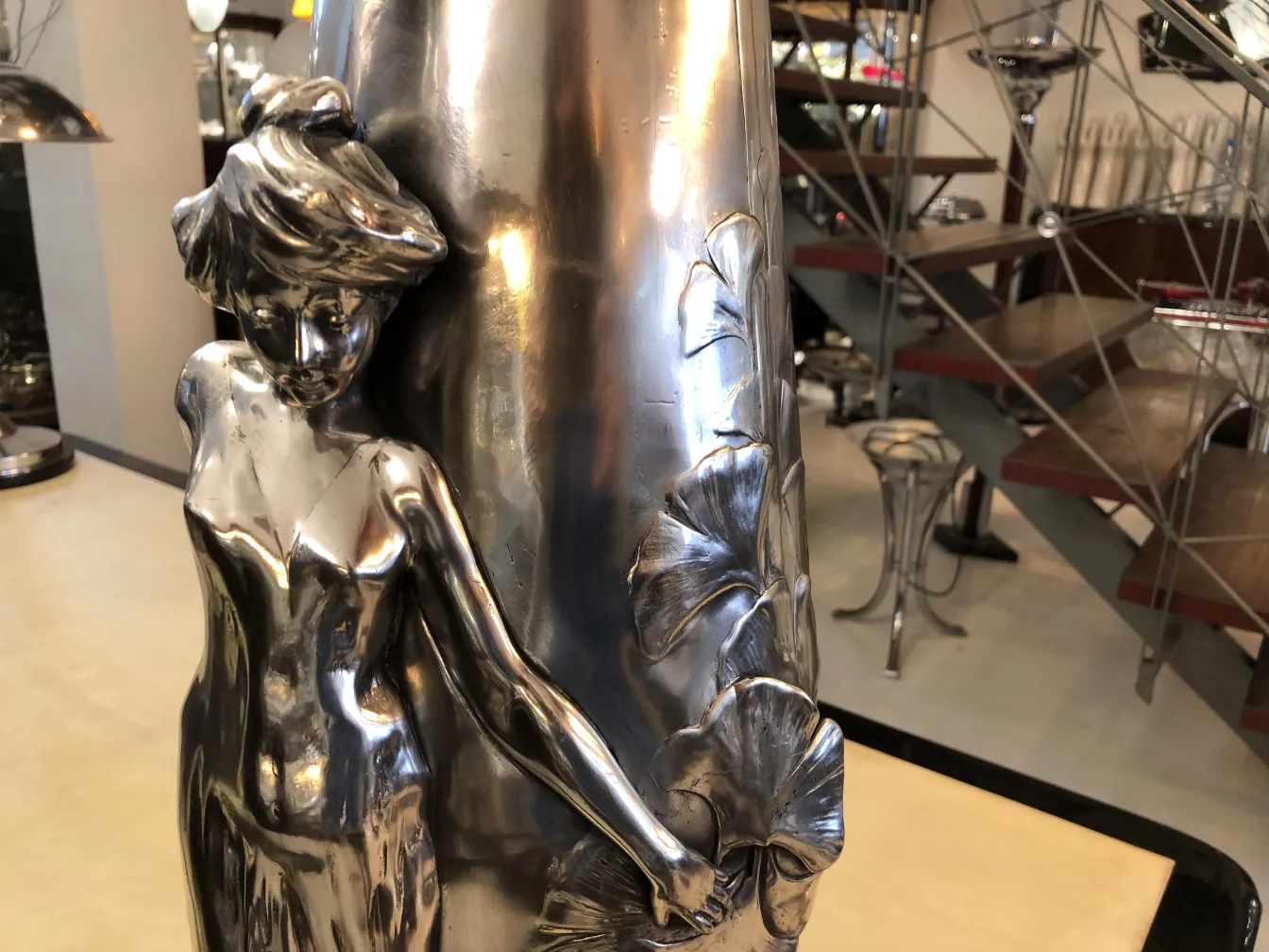 Antike Metallvase mit eleganter Frauenfigur und Blättern.