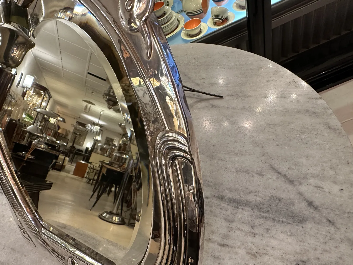 Miroir ancien Art Nouveau avec détails décoratifs, reflétant la pièce. Ambiance vintage avec des meubles.