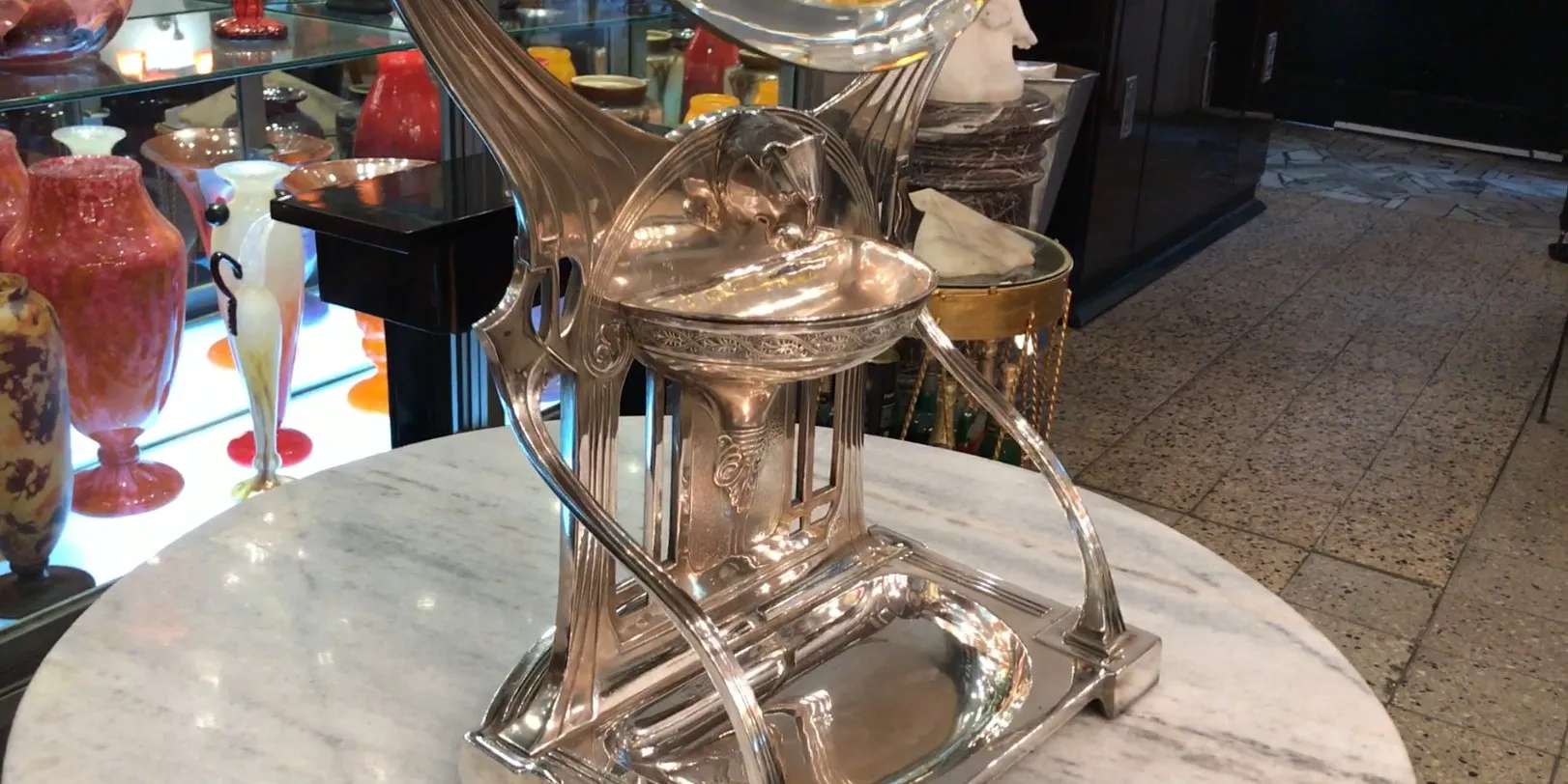 Miroir ancien art nouveau avec base décorative, entouré d'objets colorés.