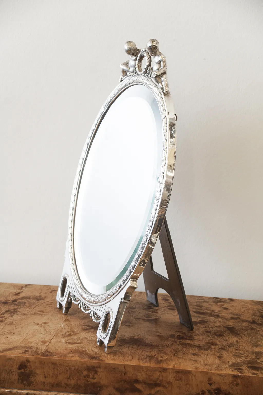 Miroir ancien de forme ovale avec décoration en haut.