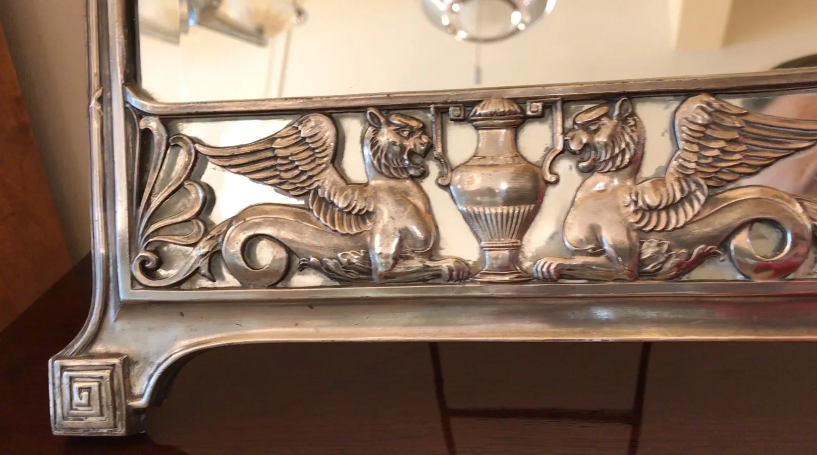 antique mirror with griffin details in the frame