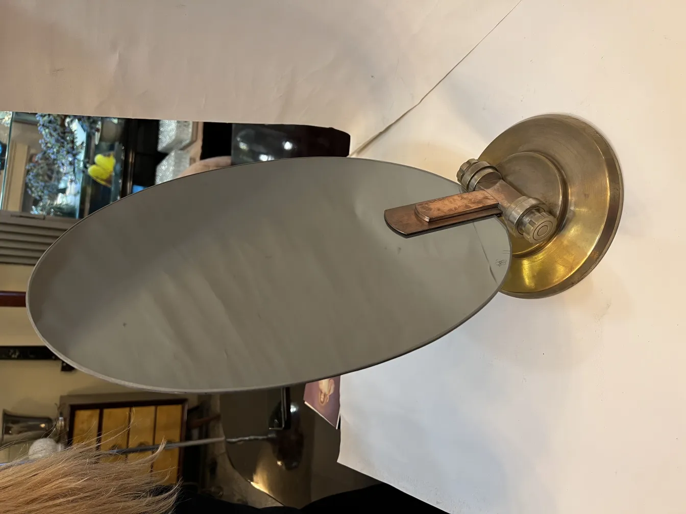 Specchio ovale antico con supporto in metallo in un ambiente vintage.