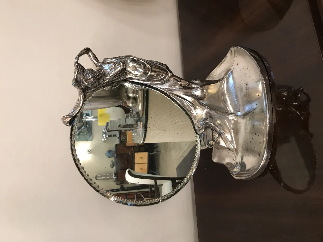 Miroir ancien avec design artistique et pieds décoratifs.