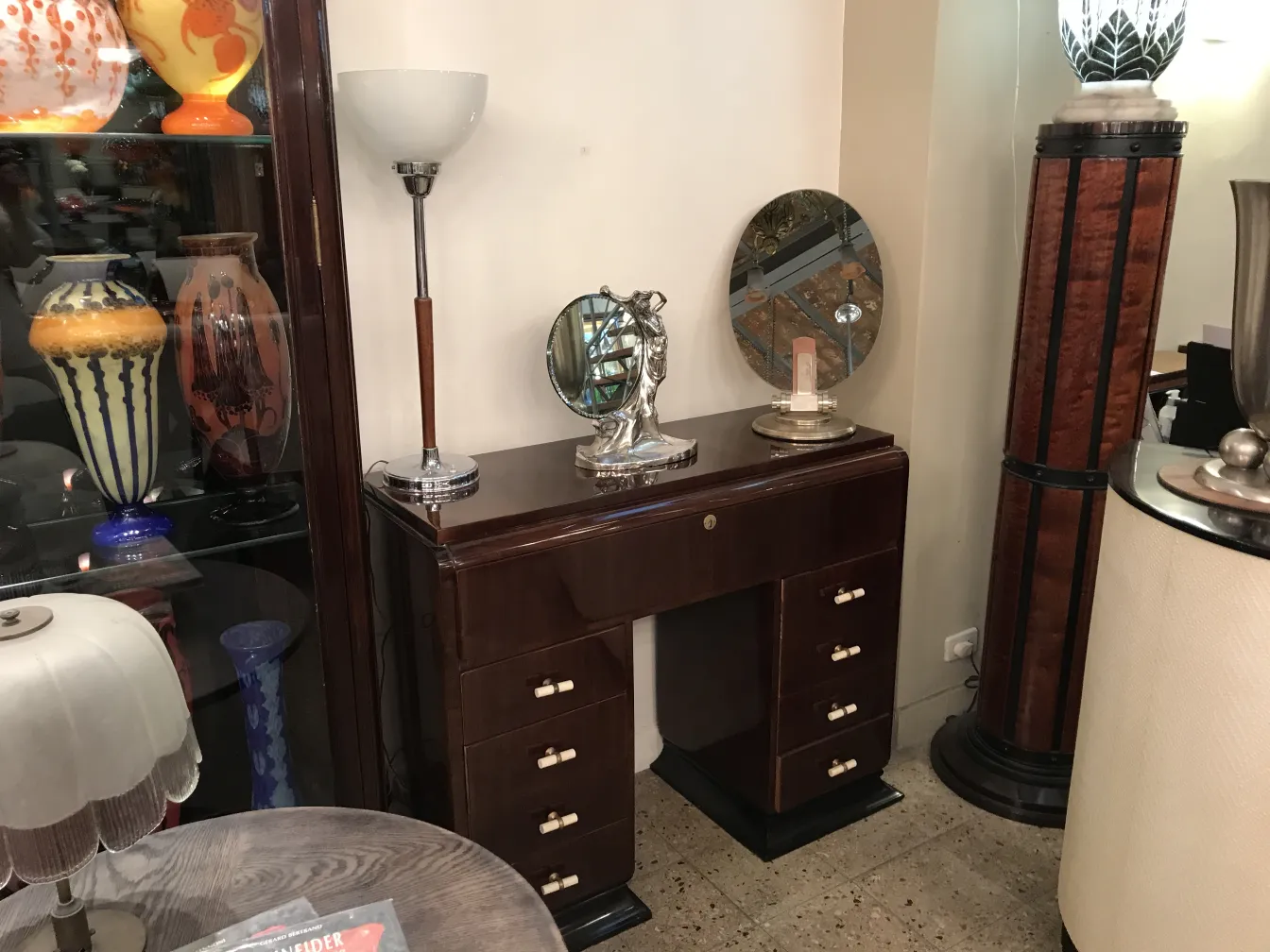 espejo antiguo ovalado decorado con detalles finos, rodeado de lámparas y jarrones.