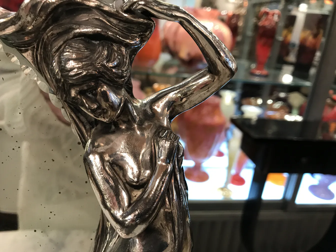 アールヌーボーのデザインを施したアンティークミラー、背景にはカラフルな花瓶。