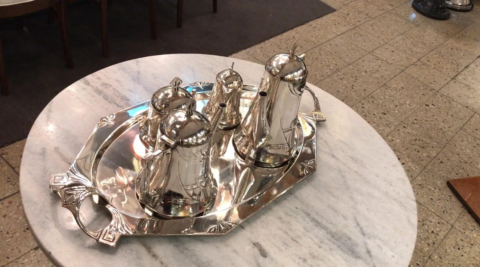 Antiguo juego de té WMF con varias teteras en una bandeja, sobre una mesa de mármol.