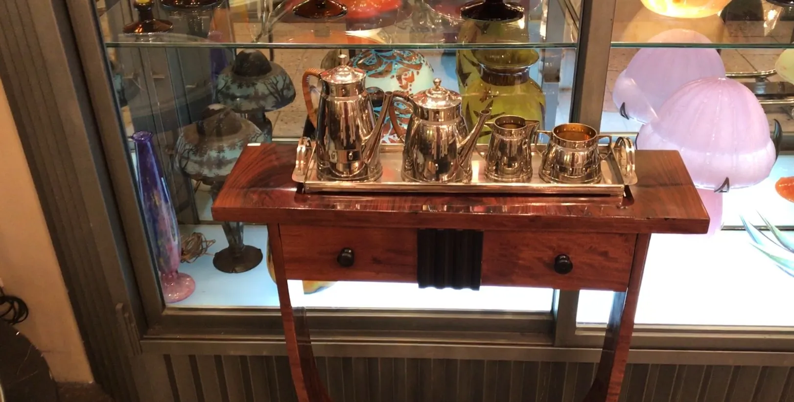 Античный чайный набор WMF на серебряном подносе, окруженный цветной посудой на заднем плане.