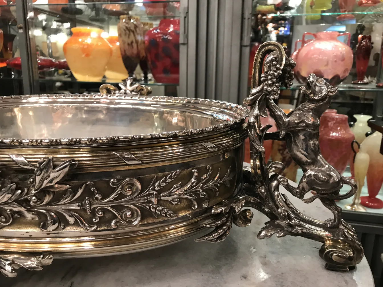 centro de mesa antigo com detalhes elaborados e um cachorro como suporte rodeado de decorações coloridas.