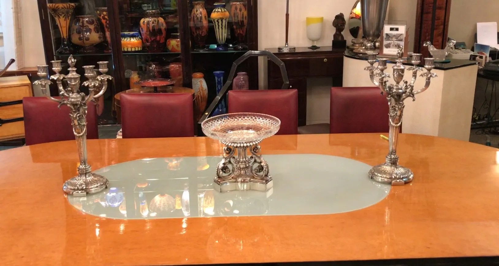 Antique centerpiece Christofle on an elegant table with candelabra and colorful decorations in the background.