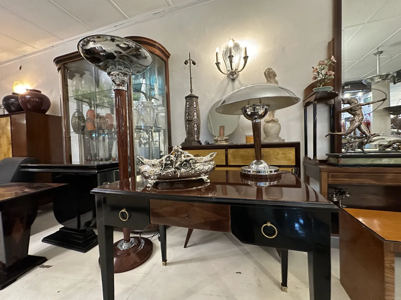 Antique decorative centerpiece on an elegant table with lamps and display cabinets.