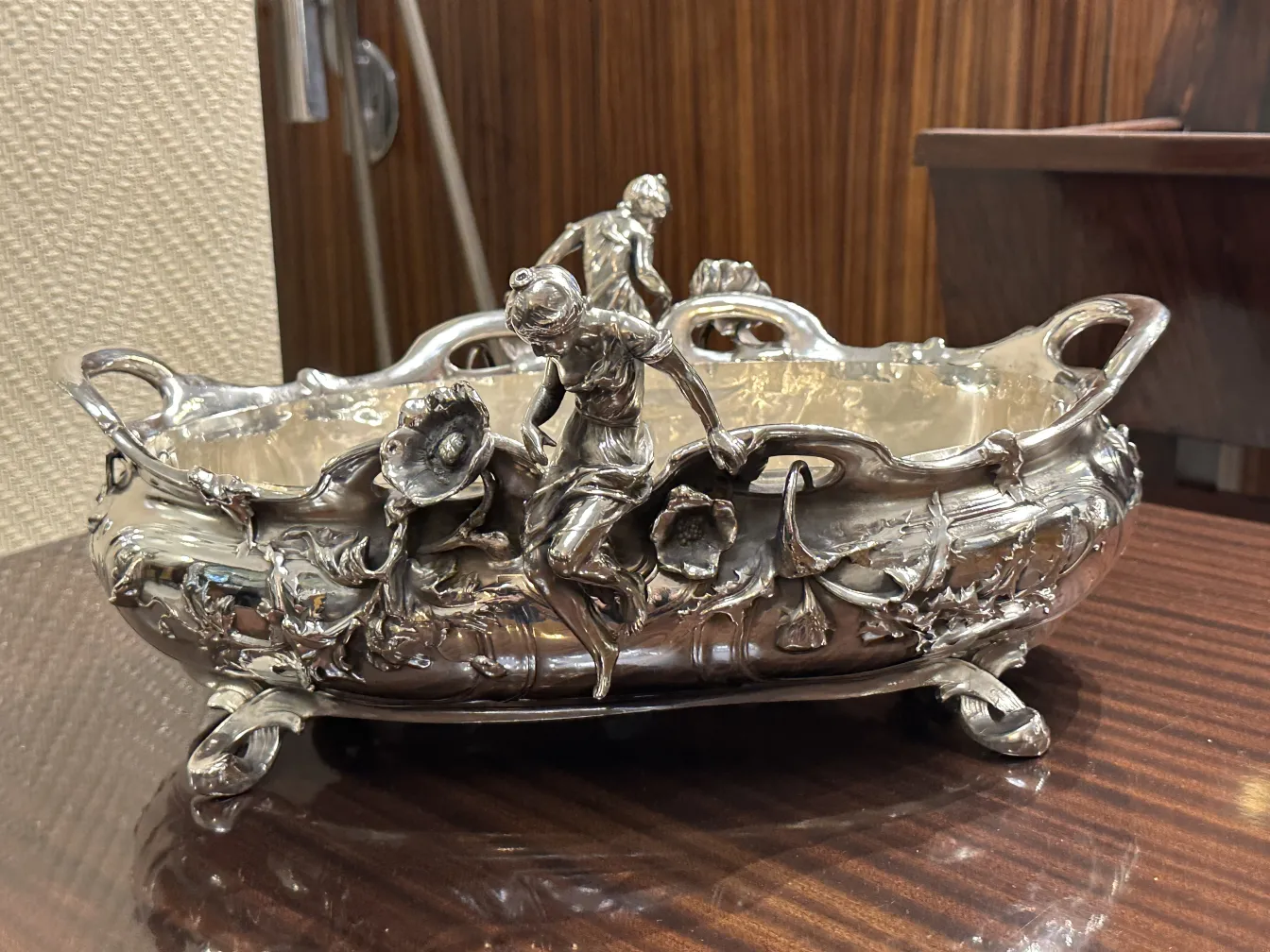 古い金属製のセンターピースには、人物と花の装飾があります