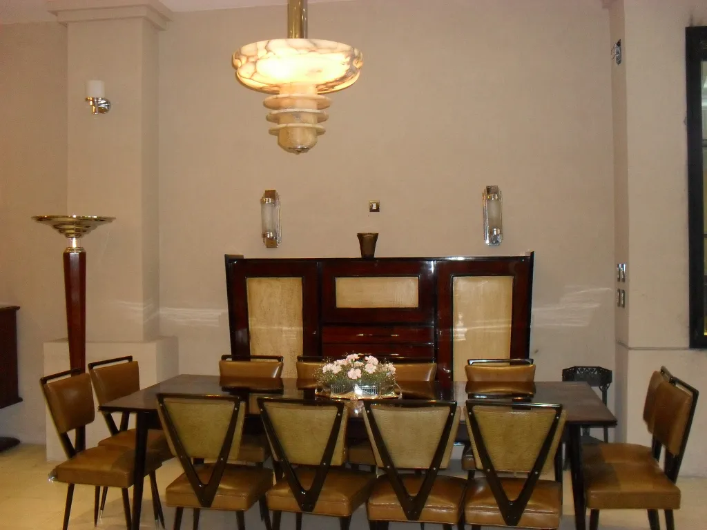 Centro de mesa antiquado WMF em uma mesa, rodeado por cadeiras elegantes em um ambiente sofisticado.