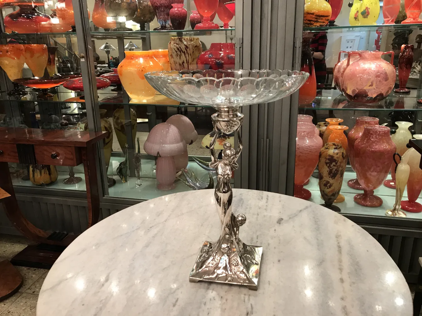 Antico centrotavola WMF esposto elegantemente con vasi colorati sullo sfondo.