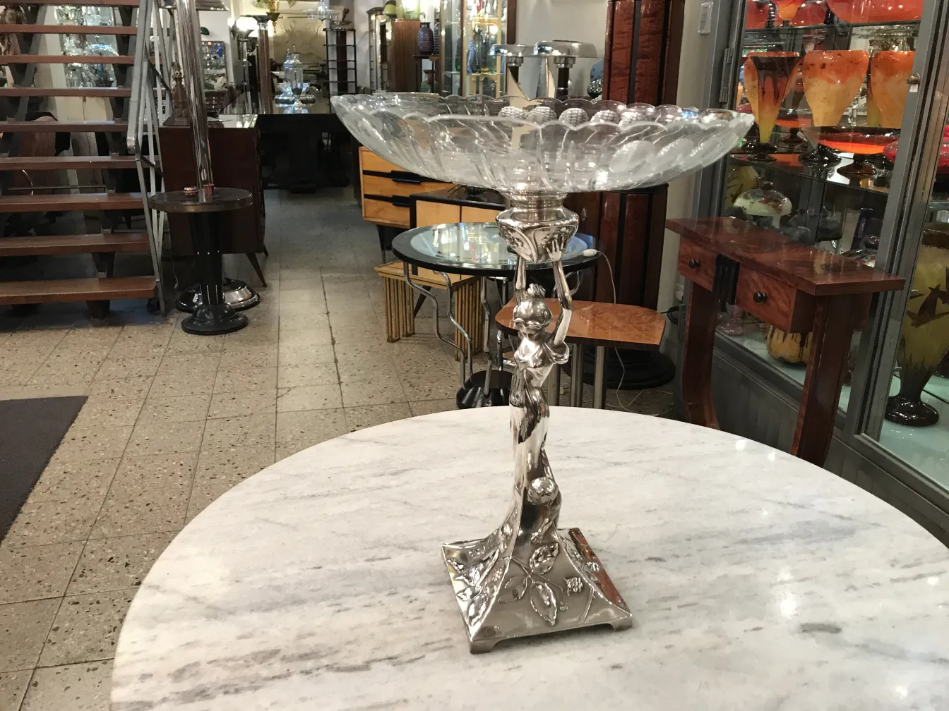 Centrotavola antico WMF in forma decorativa con base ornata, immerso in un ambiente accogliente.