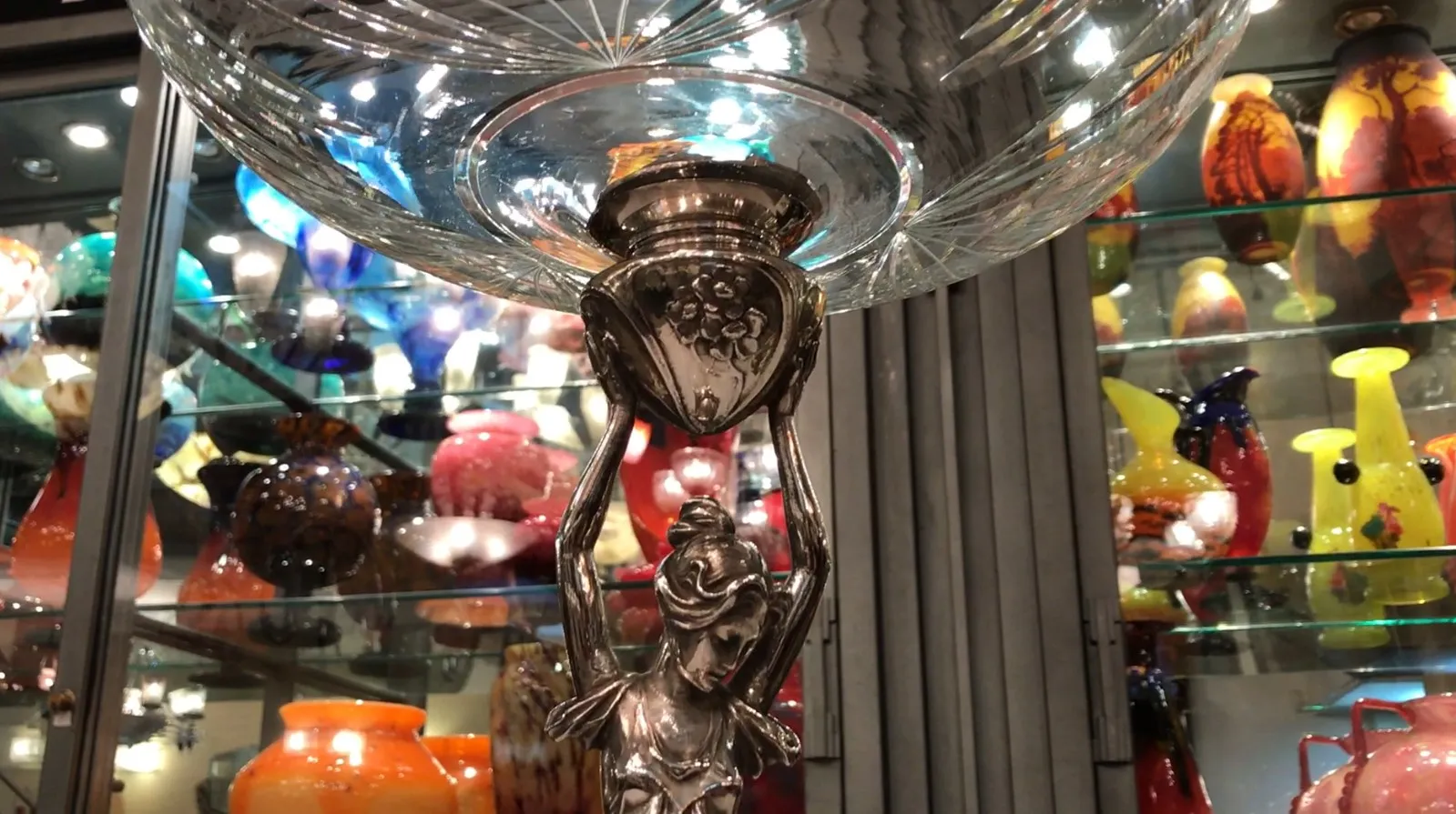 Centrotavola antico WMF con finitura elegante e design decorativo, circondato da vasi colorati.