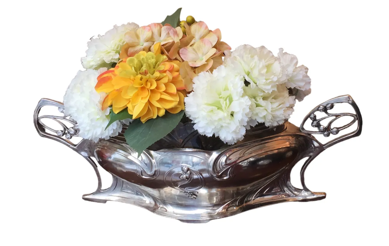 Centre de table ancien WMF avec un mélange de fleurs dans des tons chauds et froids.