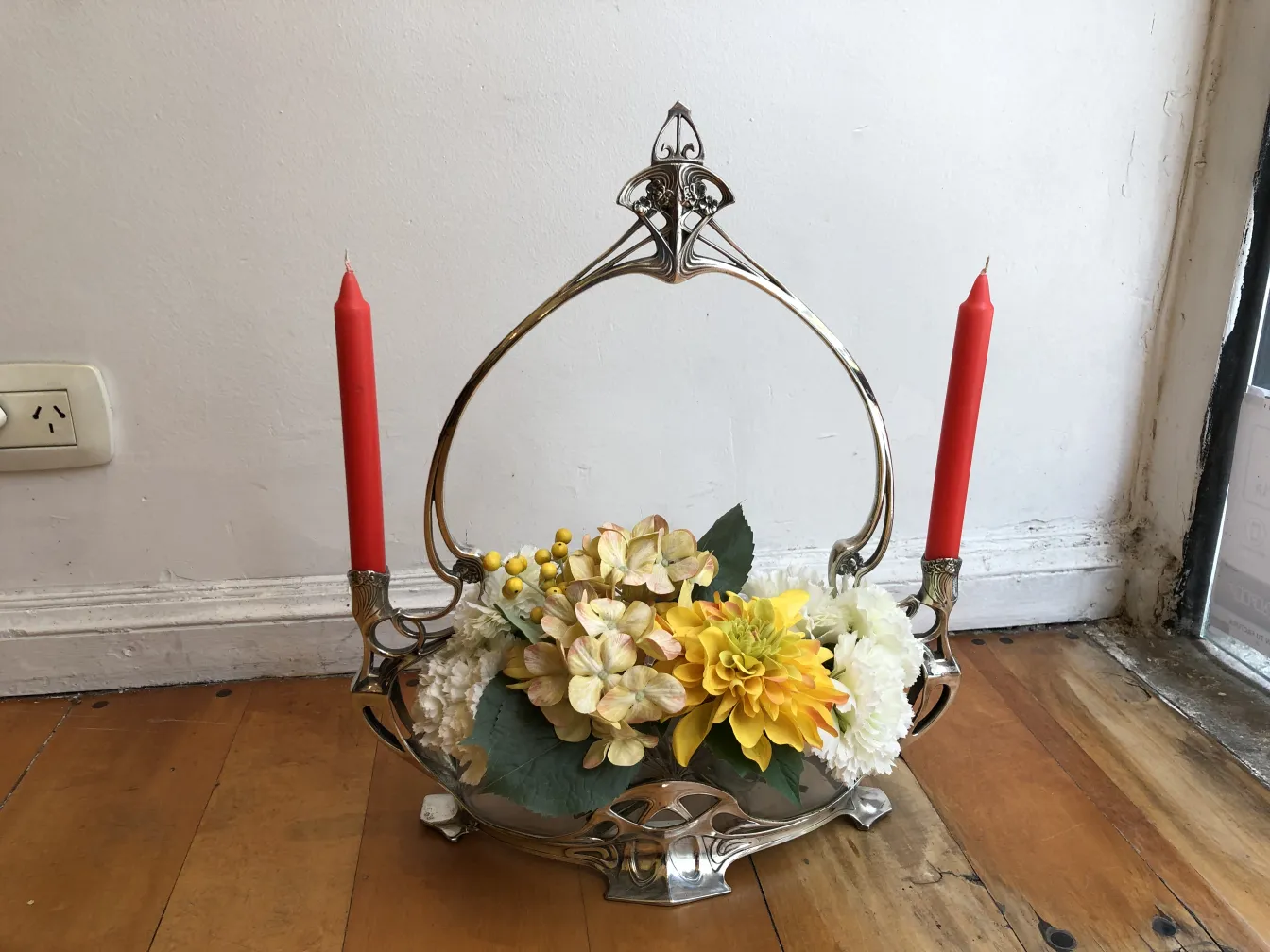 Centre de table ancien avec des fleurs et des bougies rouges.
