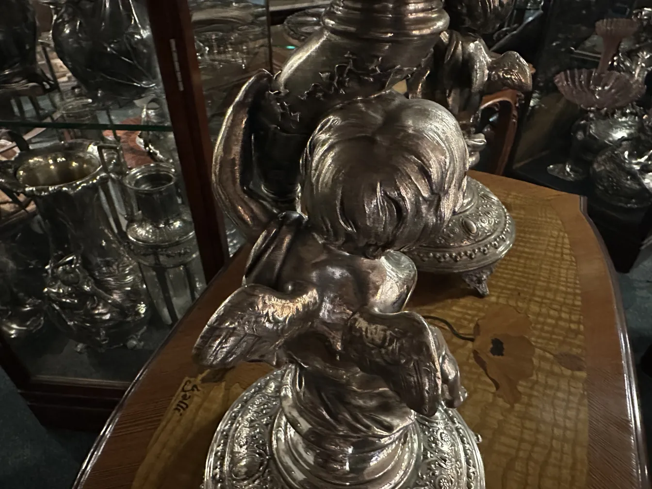 centrotavola wmf antico con dettagli decorativi e angeli nel design, circondato da altri oggetti d'epoca