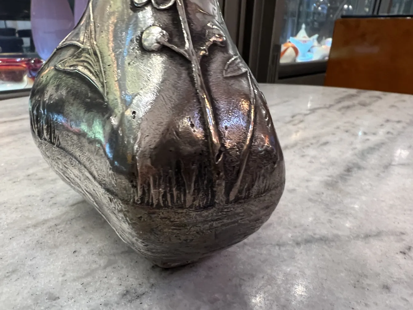 jarro antigo com detalhes decorativos e um acabamento brilhante sobre mármore