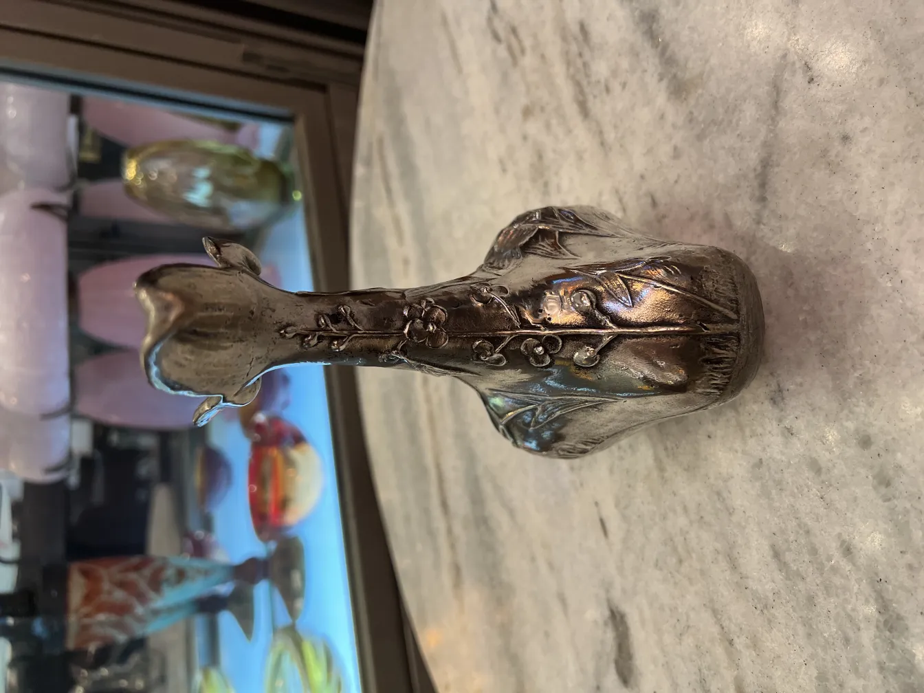 古董水瓶的正面，带有花卉装饰，背景有色彩缤纷的物品