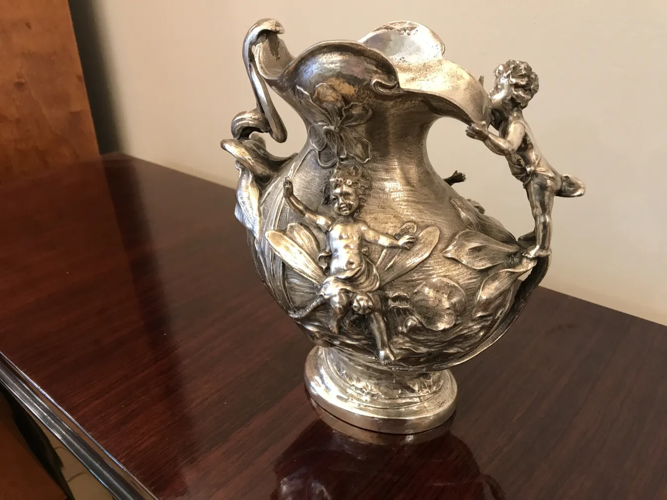 antique jar decorated with figures of children and flowers, in a classic setting