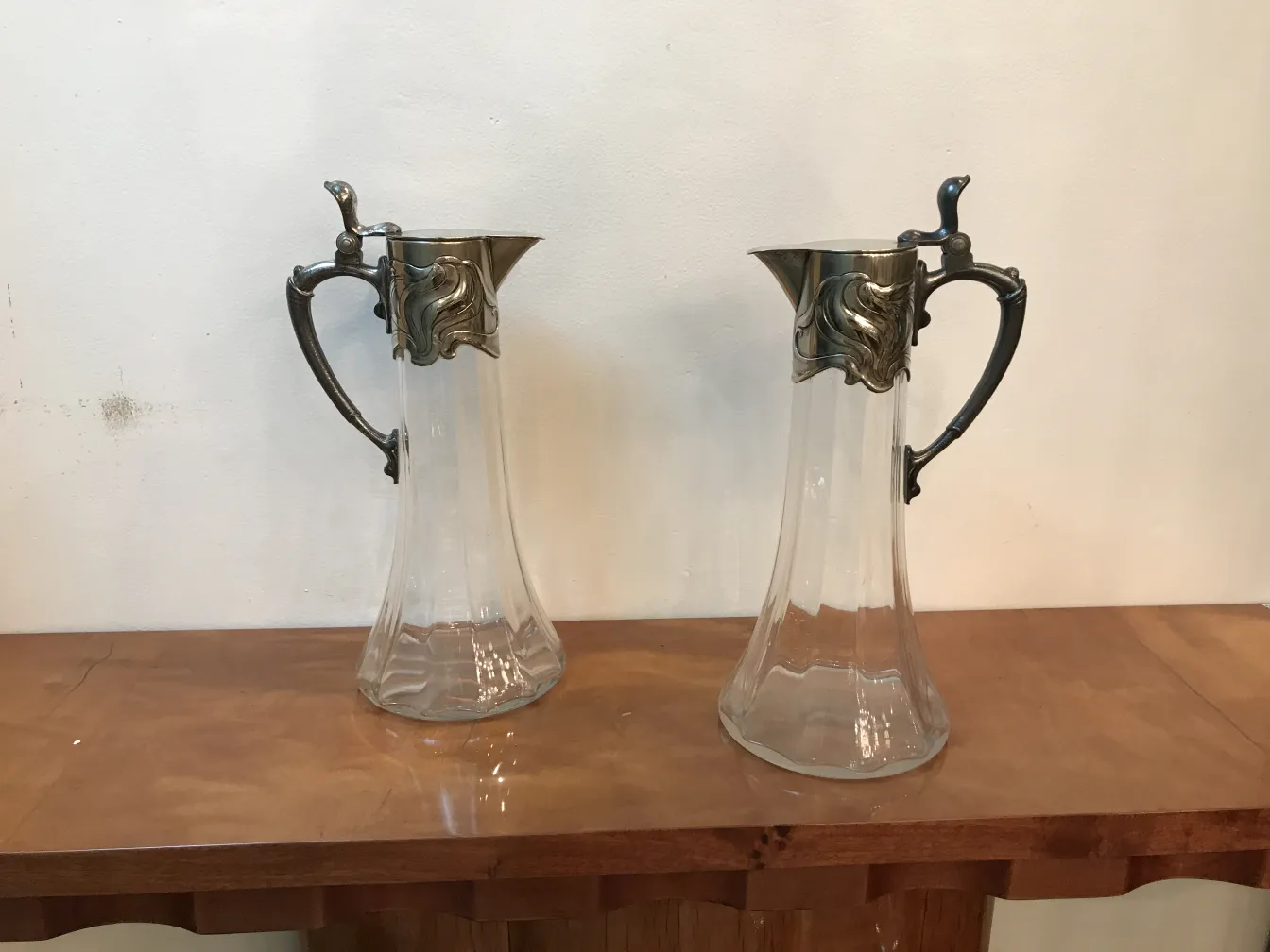 Due brocche antiche con dettagli eleganti, su un tavolo in legno.