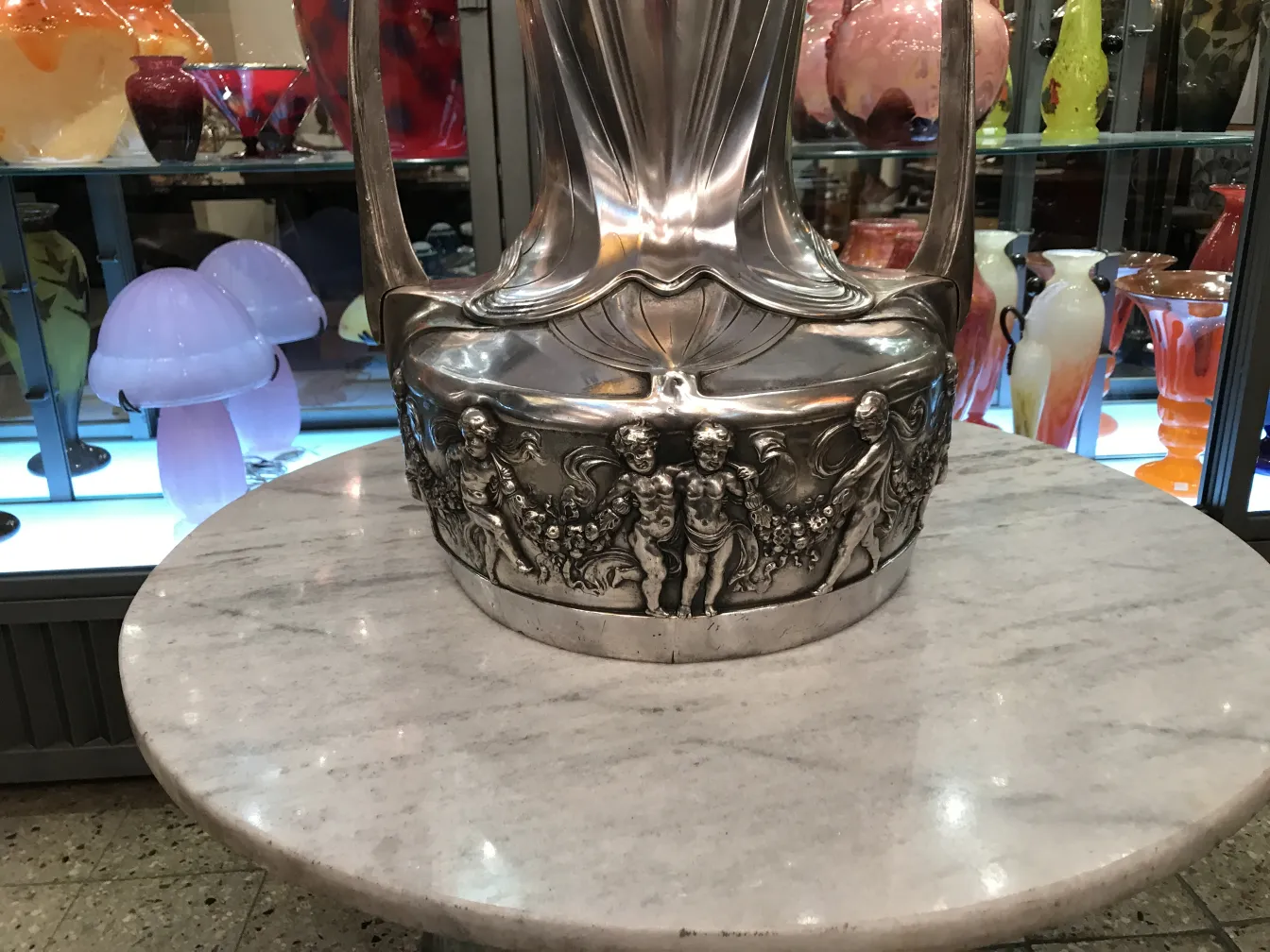 Set of 2 antique champagne coolers, decorated and shiny on a marble table. Colorful background with other items.