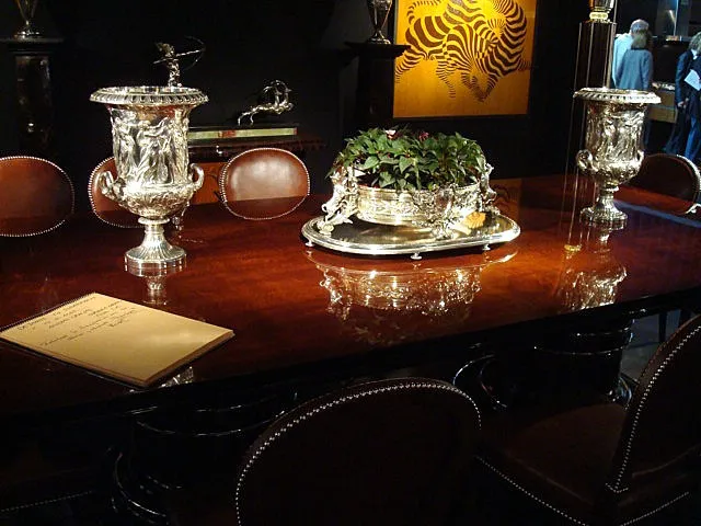 2 antique champagne coolers with decorative details, next to a wooden table