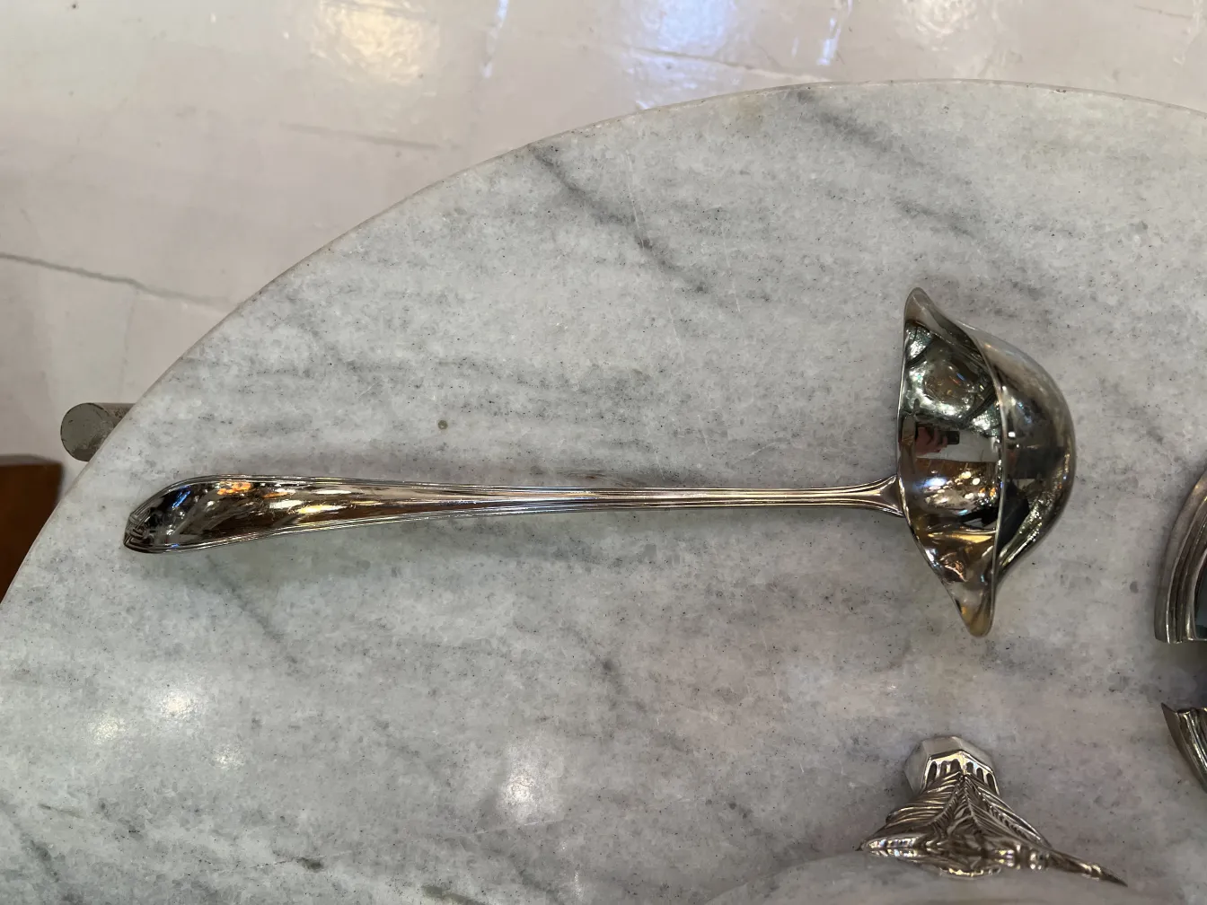 Блестящий половник рядом с чашей для пунша wmfa на мраморе