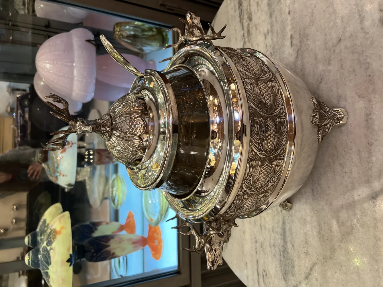 古董潘趣酒碗WMF，带浮雕细节和鹿型盖，周围是其他古董。