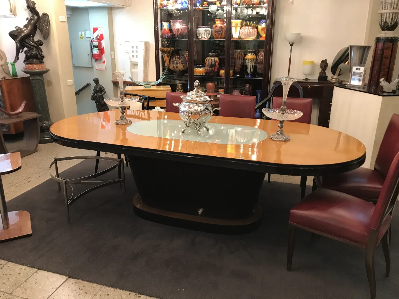 Ponchera WMF antigua en un elegante ambiente de salón con muebles de madera y sillones rojos.