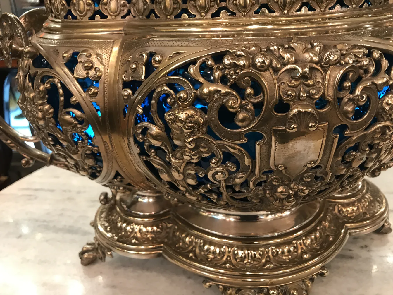 Antique WMF punch bowl with intricate design and bright blue interior, set in an elegant environment.