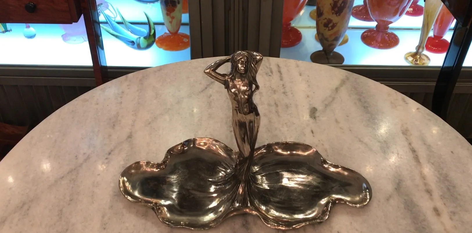 Bandeja de cartas antiga WMF com figura decorativa e curvas suaves em um ambiente acolhedor.