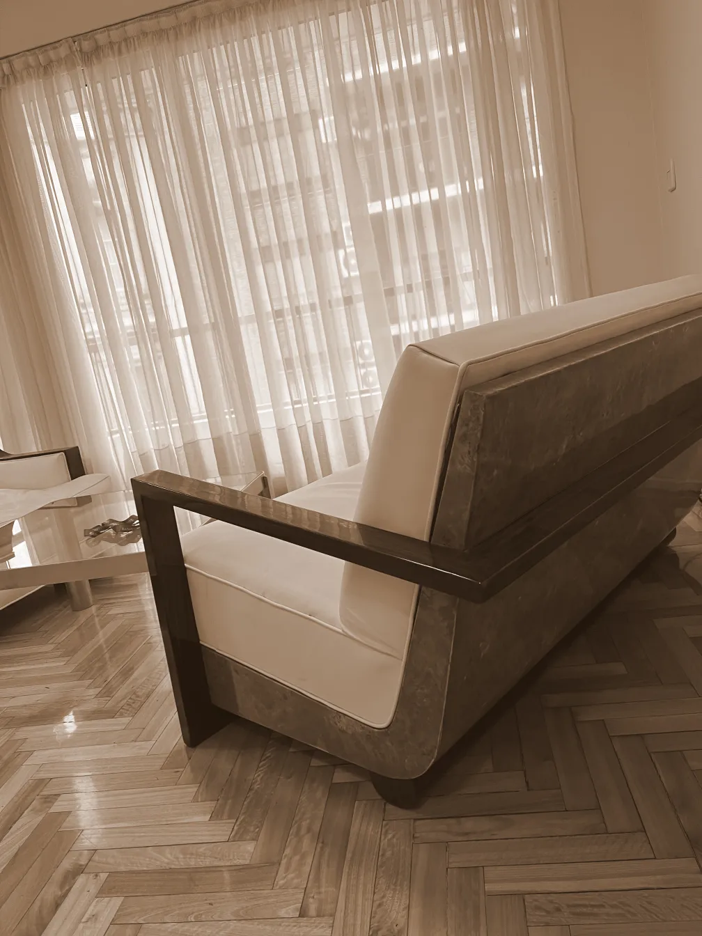 Poltrona antica con un design elegante e pulito, in una stanza luminosa con grandi finestre.