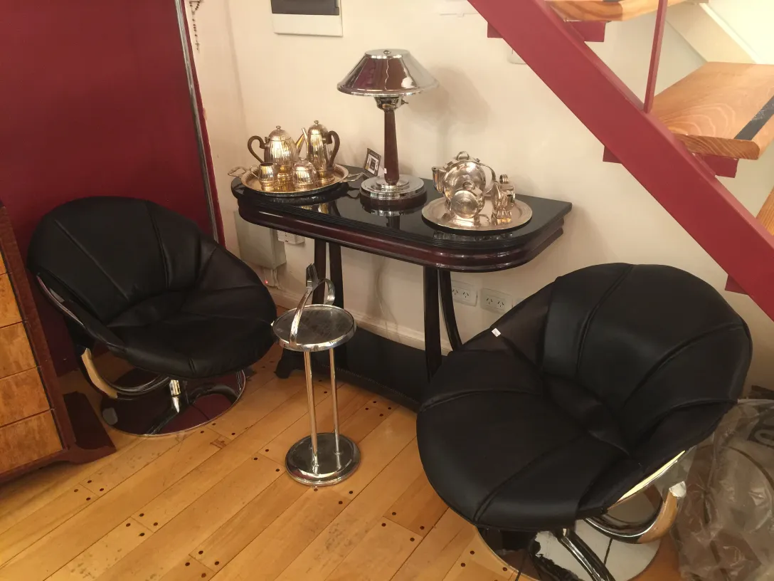 two black armchairs in a cozy setting with an antique table