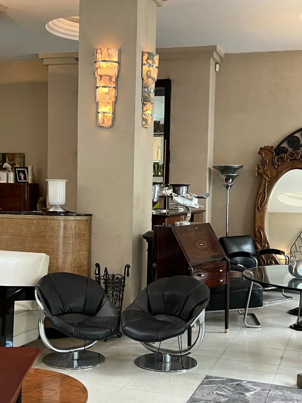 Duas poltronas antigas em um ambiente elegante com luminárias e decorações diversas.