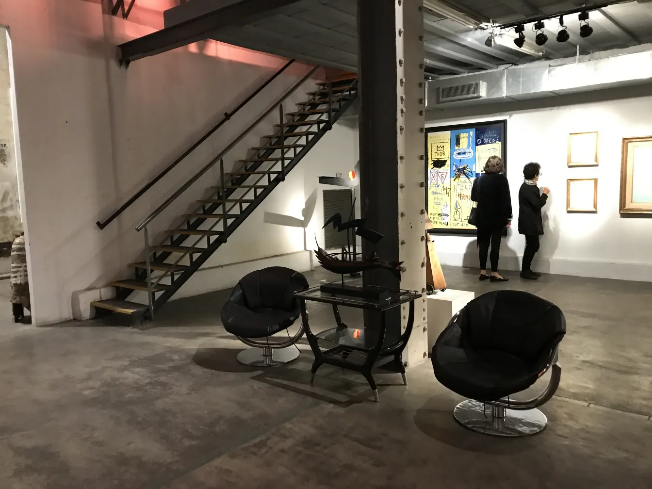 Dos sillones antiguos de forma contemporánea en una galería, rodeados de un ambiente artístico