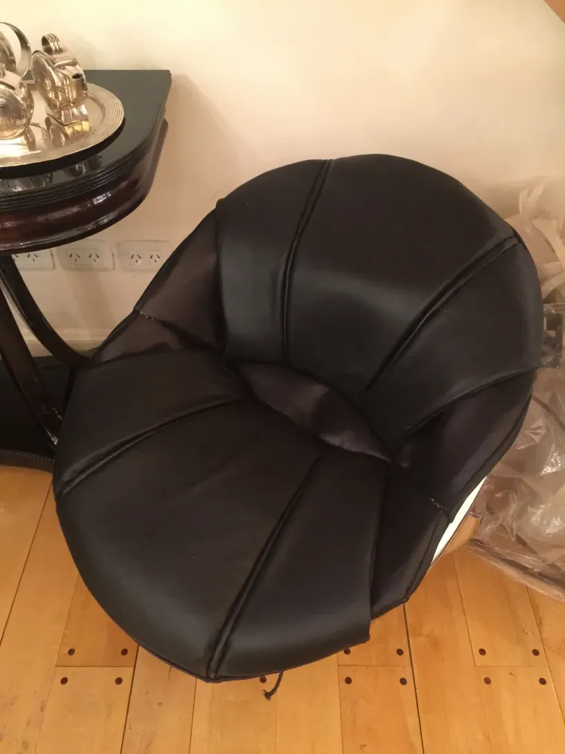 Poltrona redonda preta em uma sala com mesa antiga.