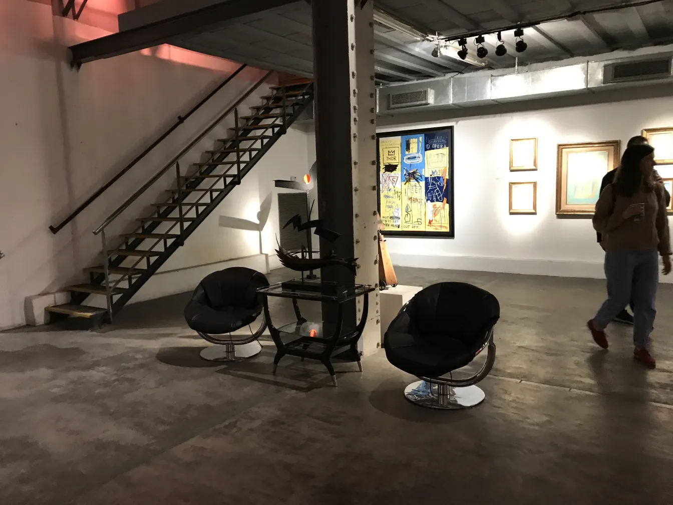 Deux fauteuils antiques dans un cadre artistique, avec des escaliers en arrière-plan.