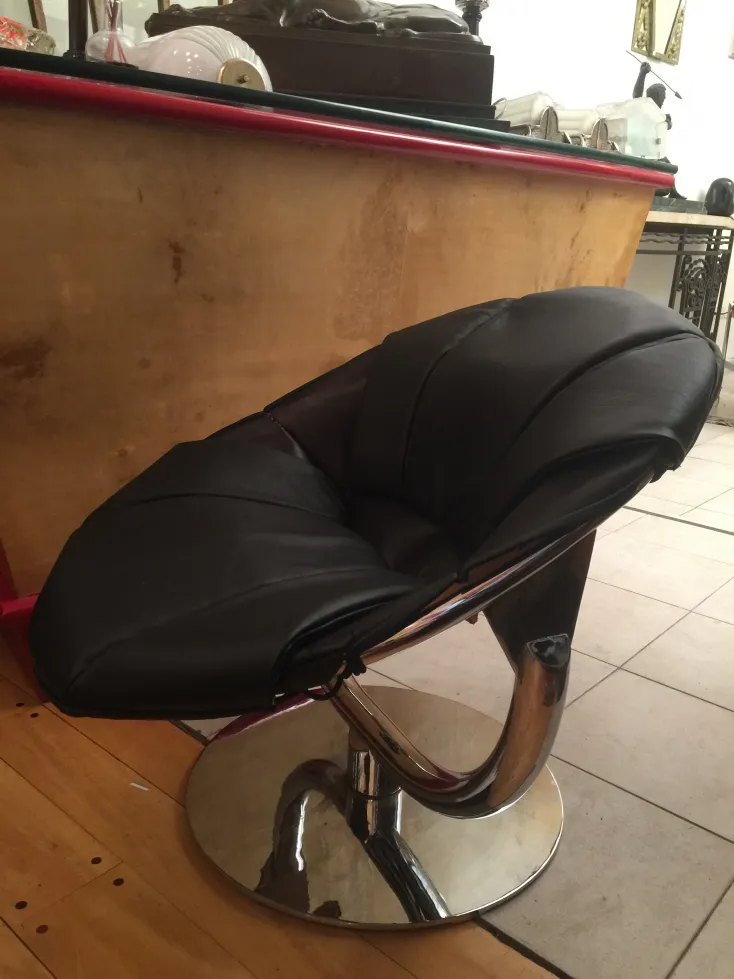 dos sillones antiguos en negro con una base metálica brillante, rodeados de un ambiente acogedor