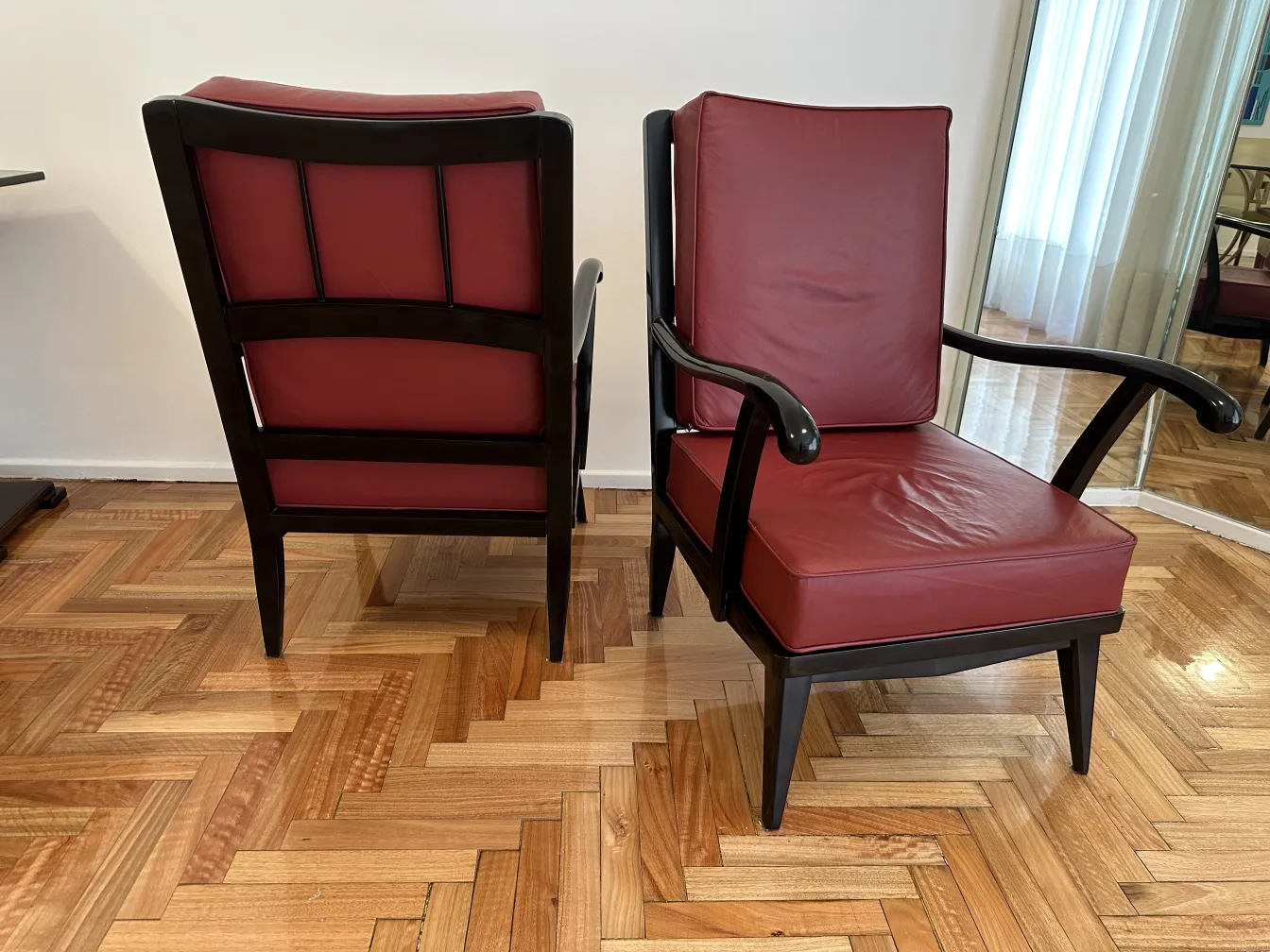 Set di 2 poltrone antiche con elegante rivestimento bordeaux, con gambe dritte e braccioli curvi, su un pavimento in legno chiaro.